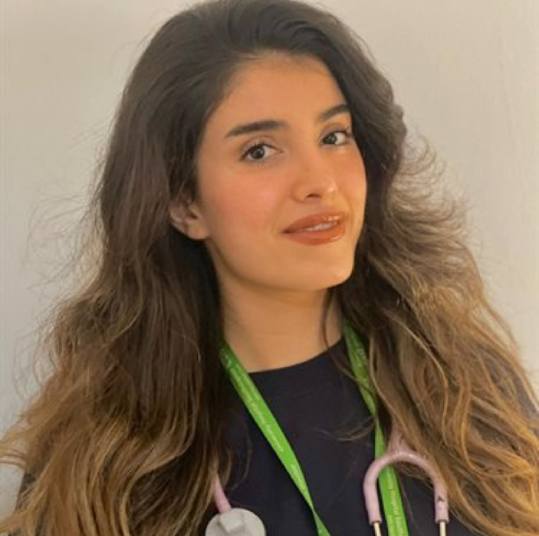 Young female healthcare worker with stethoscope and lanyard, smiling.