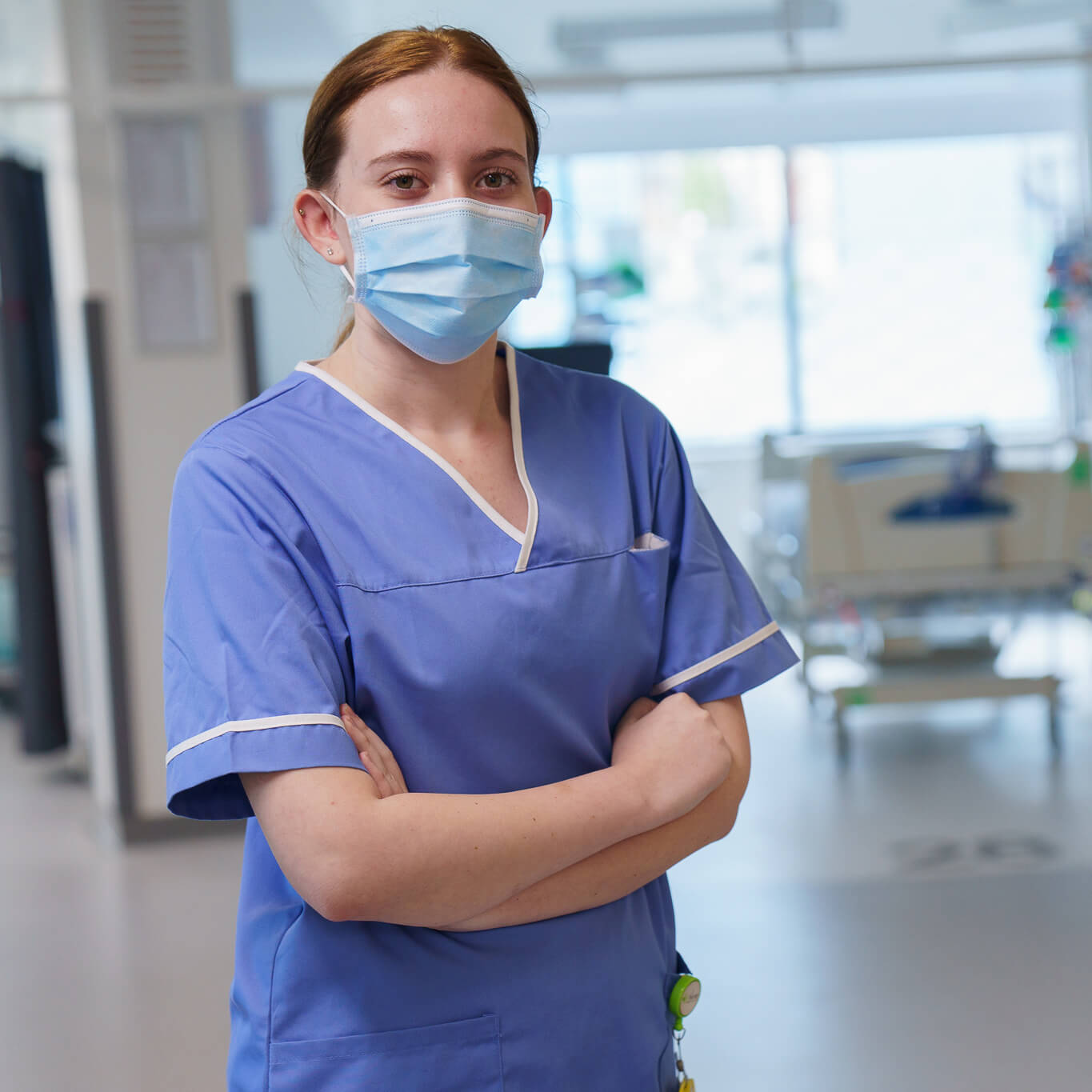 Female nurse in blue scrubs standing confidently