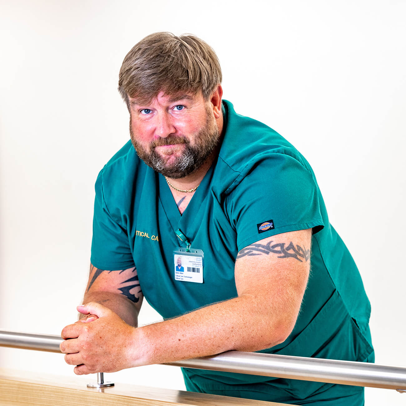 Male healthcare worker in green scrubs by railing