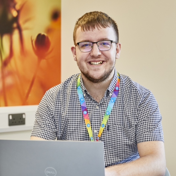 Smiling man with glasses at desk with laptop