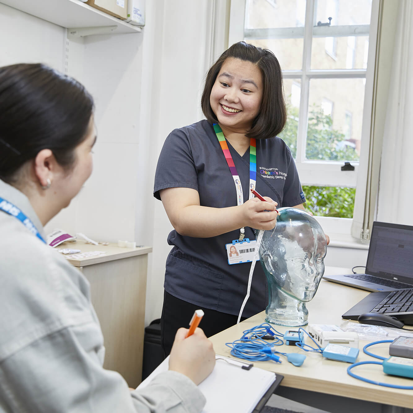 Healthcare instructor showing head model to student in classroom.