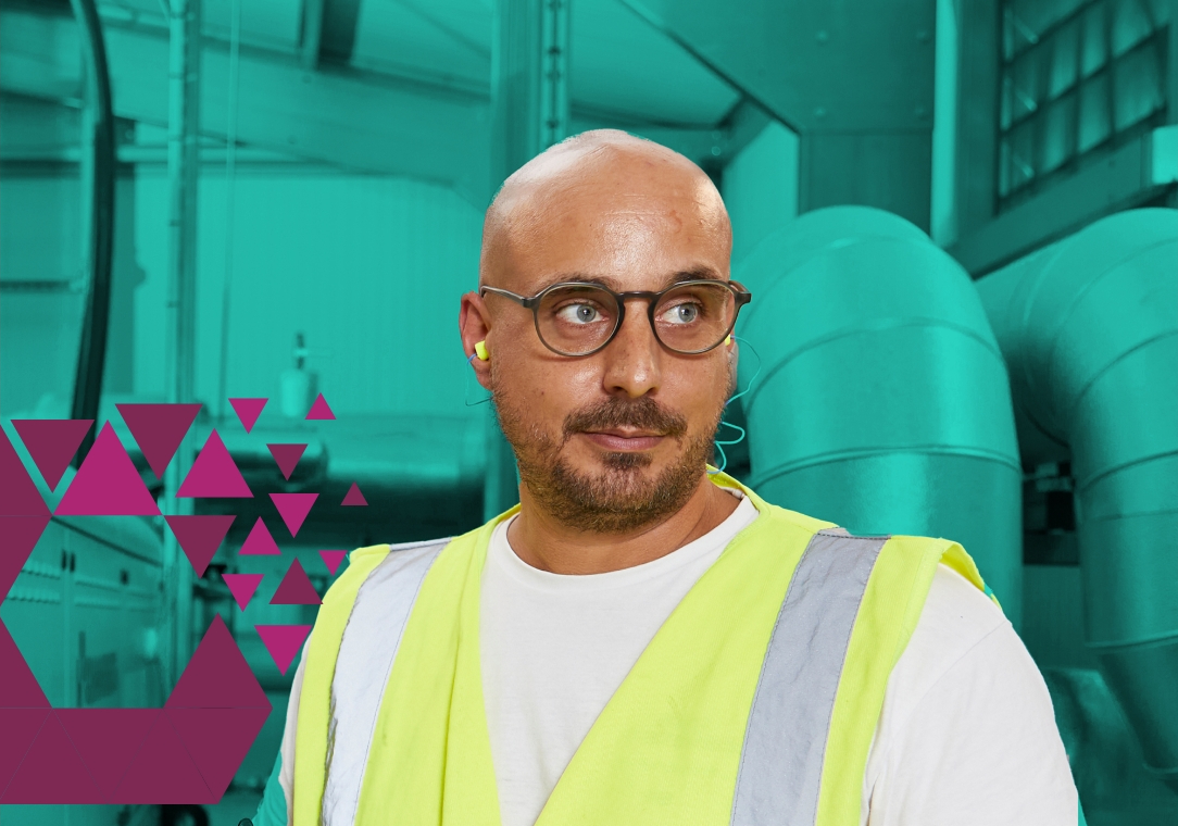 Man in safety vest standing near green industrial machinery