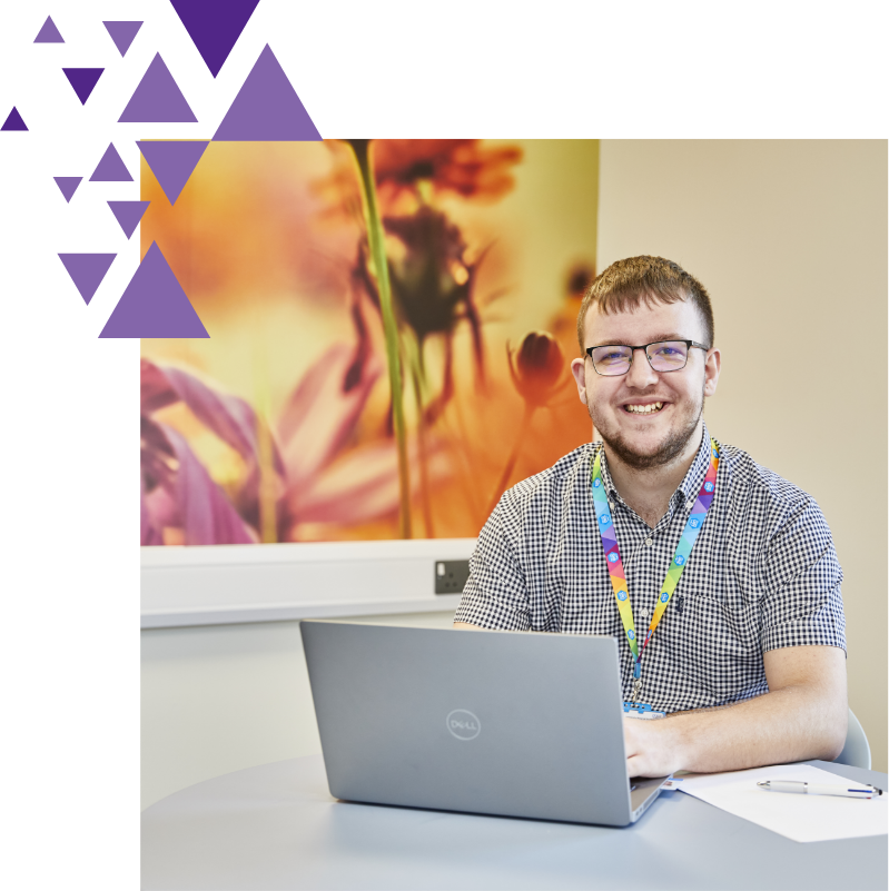 Smiling man at desk with laptop and floral background