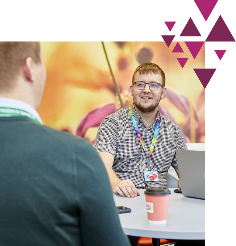 Smiling man in plaid shirt talking in a colorful office