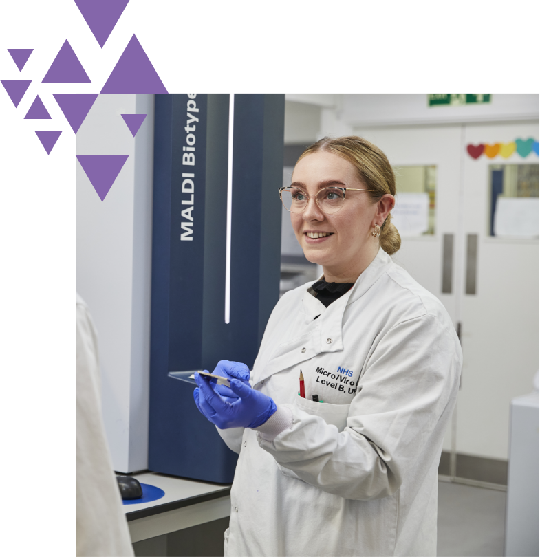 Smiling female scientist with smartphone in lab near MALDI Biotyper