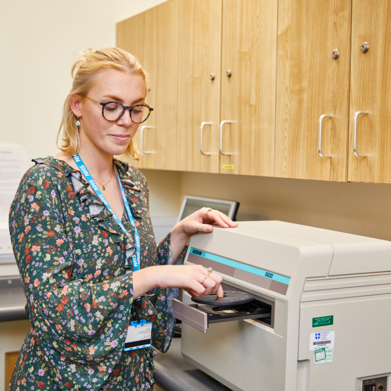 Woman using a printer in an office with wooden cabinets