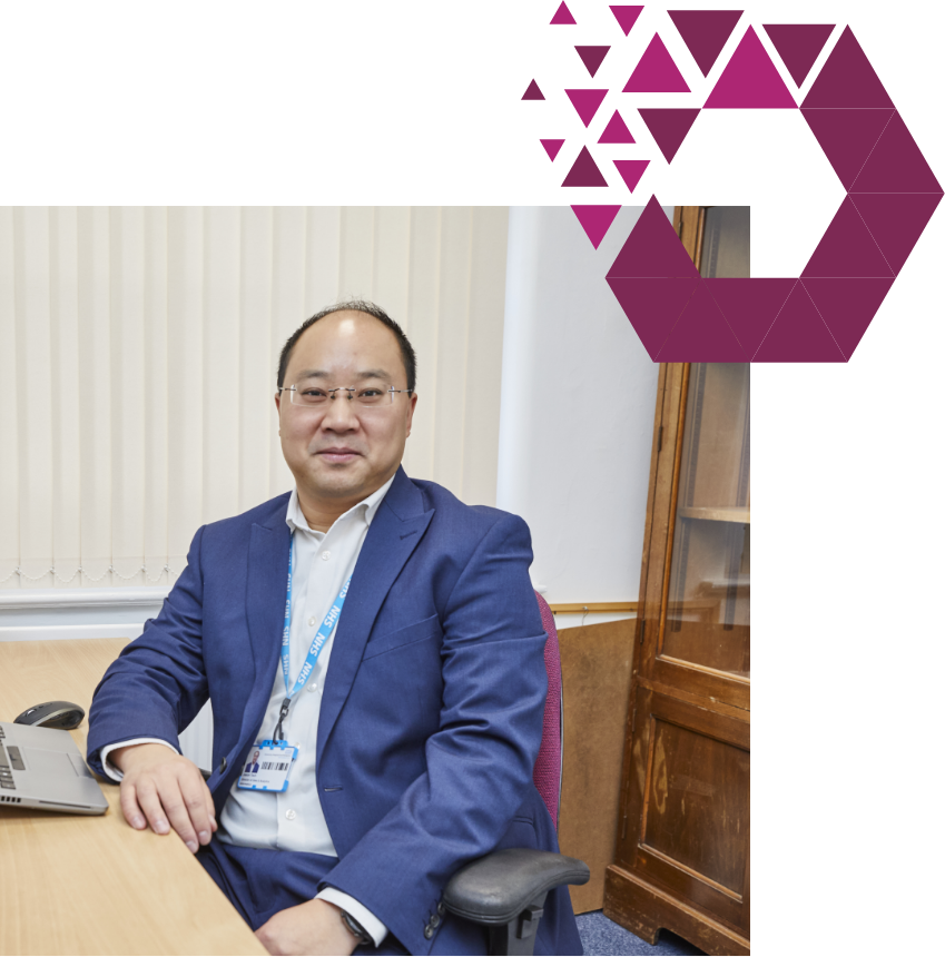 Man in business attire smiling at desk with purple shape