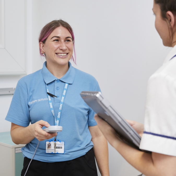 Smiling female healthcare worker with pink hair in clinical setting