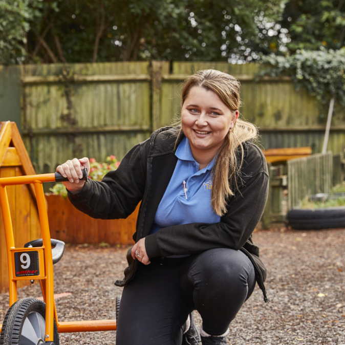 Smiling woman leaning on an orange go-kart outdoors