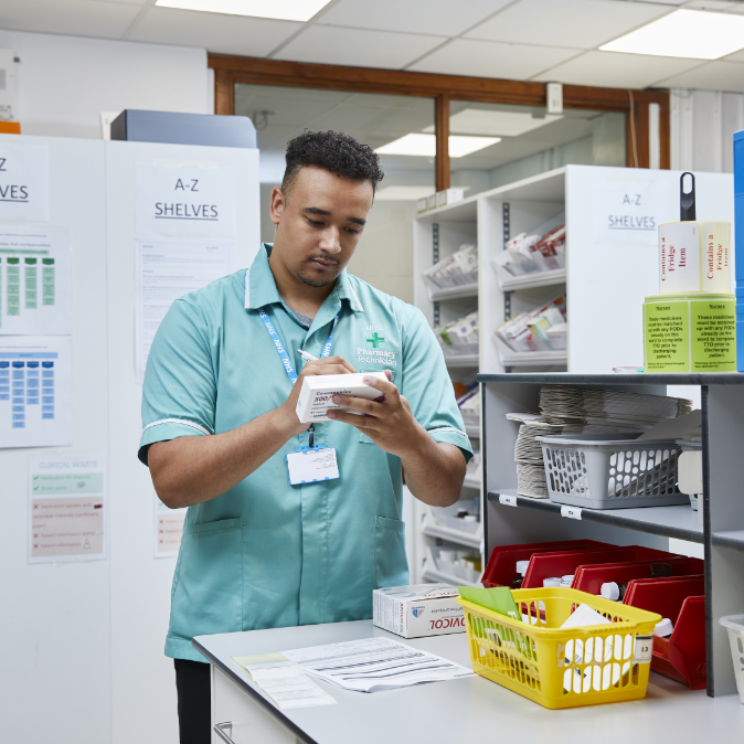 Male pharmacy worker checking inventory in a storeroom
