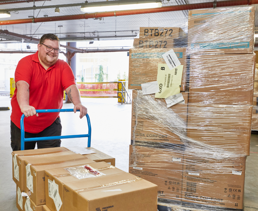 Worker moving boxes with a hand truck in a warehouse