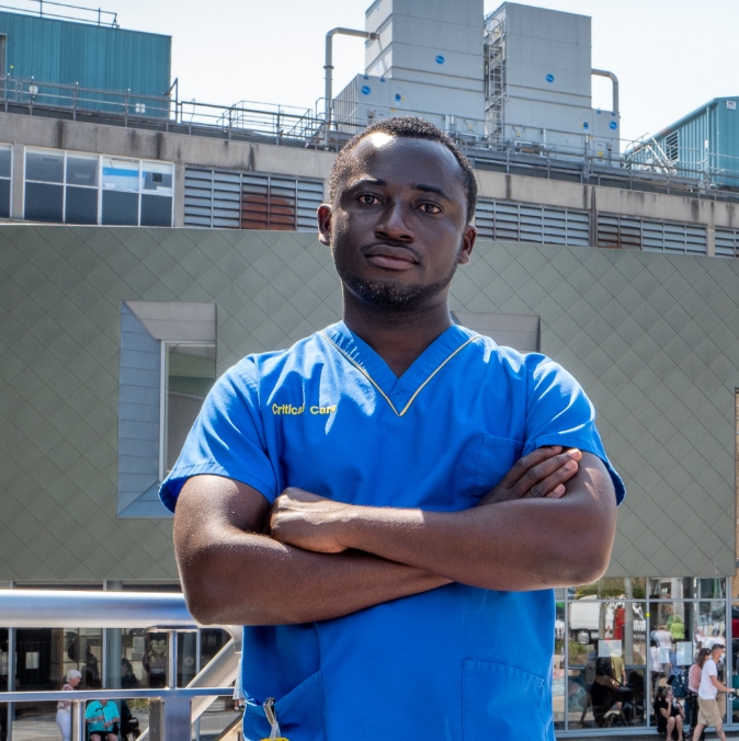 Male healthcare worker in scrubs standing outside hospital