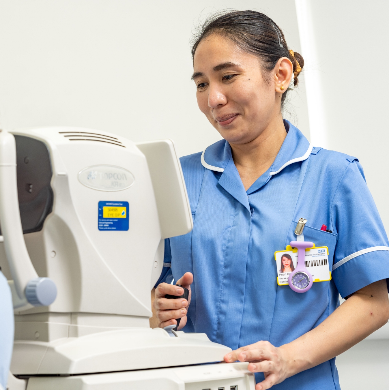 Nurse in scrubs using eye exam machine